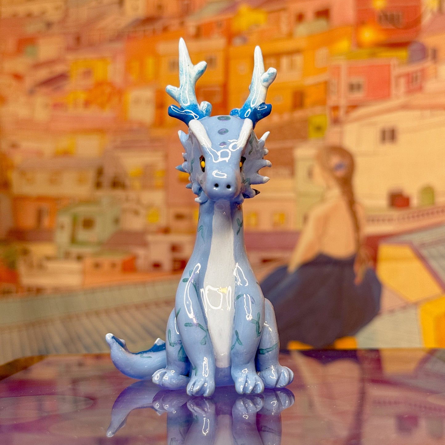 Blue dragon figurine on a reflective surface with a colorful abstract background